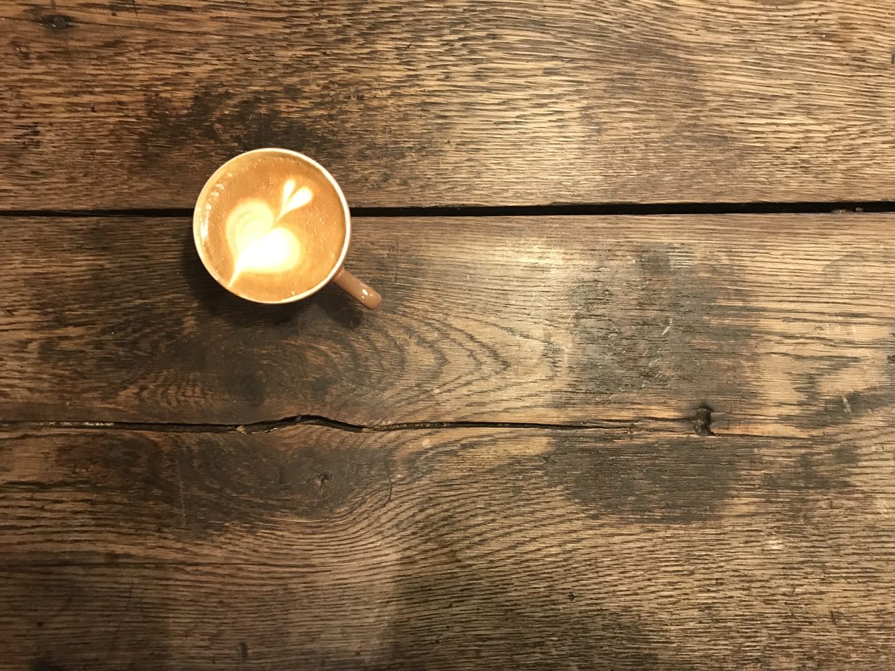 Cappuccino met latte art op de oude houten tafel